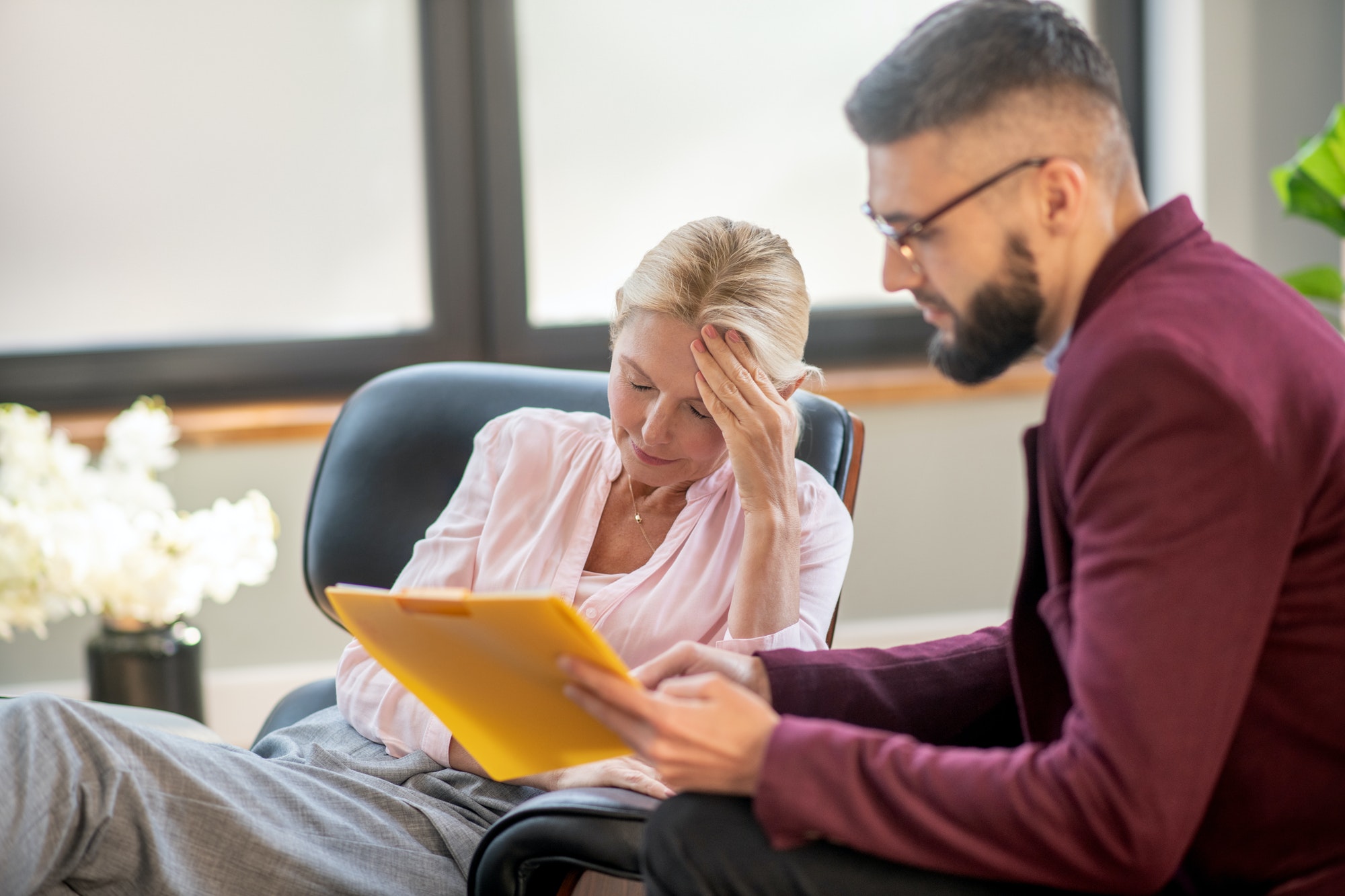 Blonde mid-aged woman having headache during psychoanalysis